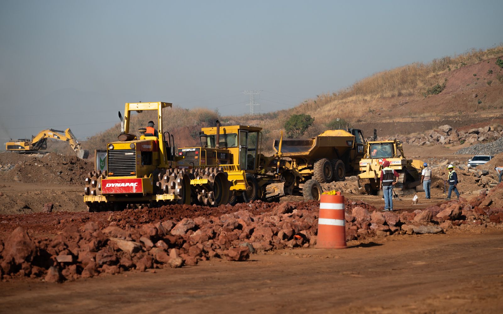 Compactador, motoniveladora y camión articulado en frente carretero